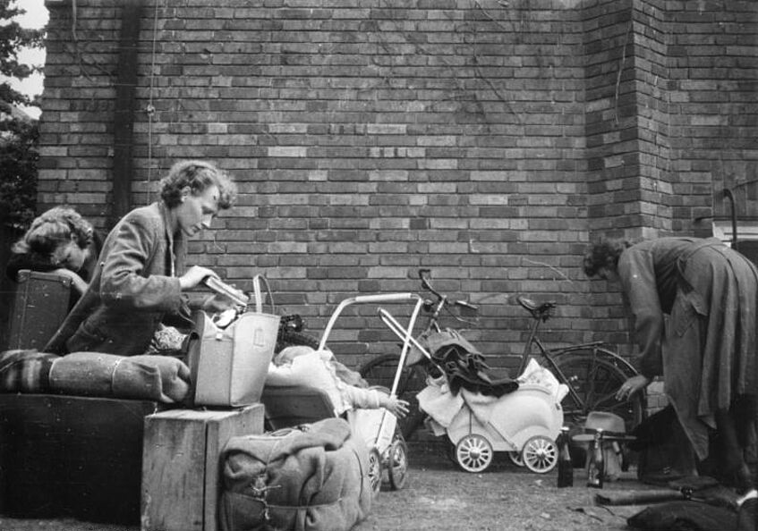 Schwarz-weiß Bild von drei Frauen und einem Baby, zwei Kinderwägen und ein Fahrrad sind auch zu sehen.